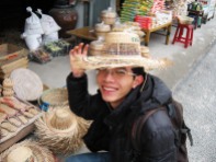 Trying on a bamboo hat at a craft village in Ninh Binh province, south of the Capital